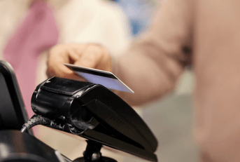 Close up of a senior man paying with credit card on self-service cash register in supermarket