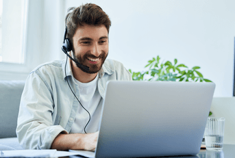 A man wears a headset while using his laptop.