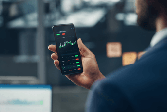 Man holding a phone showing a stock market chart