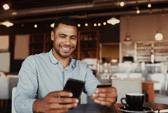 a man smiles while holding his credit card