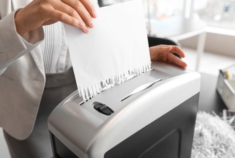secretary destroying paper sheet using shredder in office