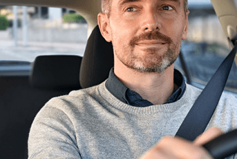 A man looks in the rearview while driving his car and gripping the steering wheel.