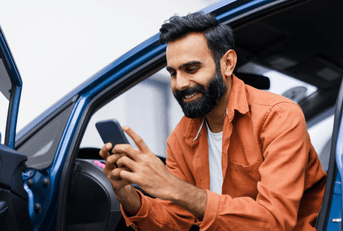 person looking at phone while leaning out of car