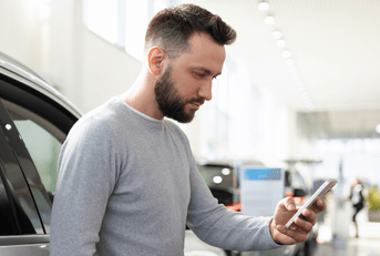 person looking at phone in car dealership