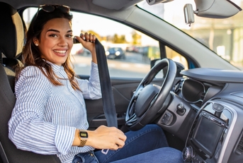 Smiling woman buckling a seatbelt