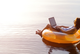business woman working on a laptop in an inflatable ring in the water