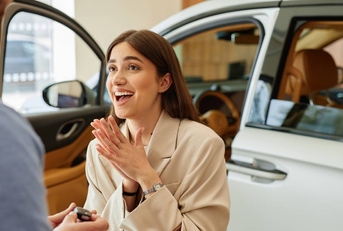 happy woman receiving car key at dealership