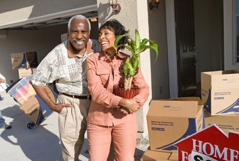 african american couple with belongings moving into a new house