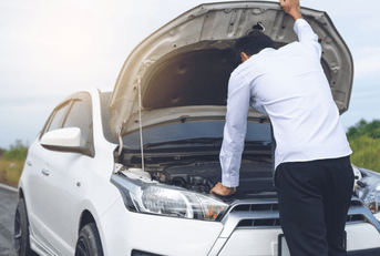 A man lifts the hood of his vehicle and examines his engine.