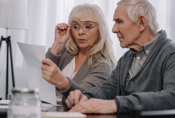 couple sitting at table and looking at bills