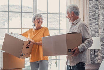 Mature couple carrying cardboard boxes