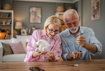 Senior couple count money from the piggy bank