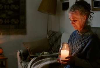 woman sitting on sofa holding large candle jar