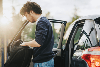 teen with backpack standing outside car