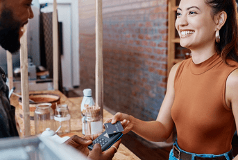 A woman uses her credit card to make a purchase at a cafe.