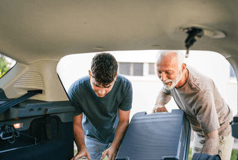 senior helping grandchild load car