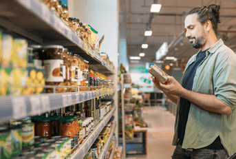 Man looking at an item in his hands while shopping at the grocery store