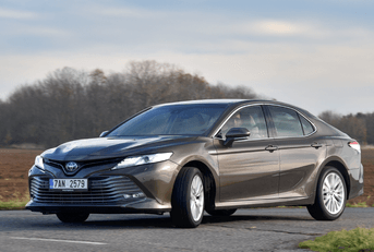 A man drives a dark gray Toyota Camry. 