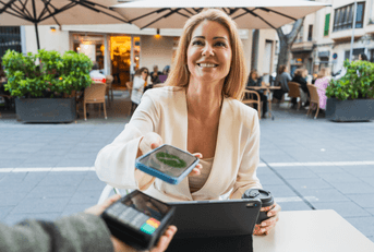 A woman smiles while using her phone to make a payment.