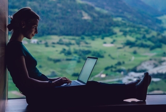 Woman in a scenic location working on a laptop
