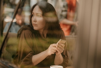 Gen X woman looking pensively out a window at a cafe