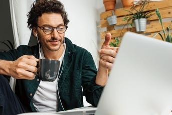 man with coffee mug working on laptop from home