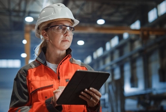 woman in a hard hat with a tablet working in a warehouse