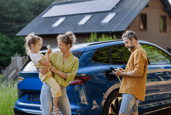 Couple with child in front of a car and house