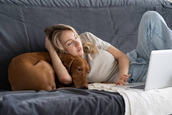 Woman working from home on couch with dog