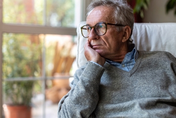 senior man looking out of window at home  