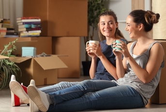 Young women sitting on floor of new home drinking coffee