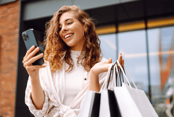 person looking at phone holding shopping bags