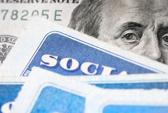 Dollar bill with Benjamin Franklin's eyes looking and Social Security cards