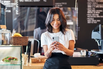 Person working at cafe using their mobile phone in front of the counter