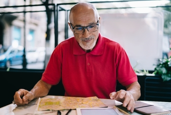 Bald man wearing glasses and looking at papers on the table