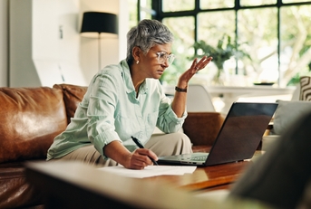 Woman looking confused with laptop and notes