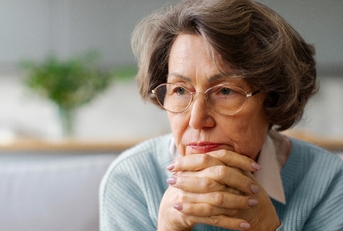 Older woman with hands crossed under her face looking worried