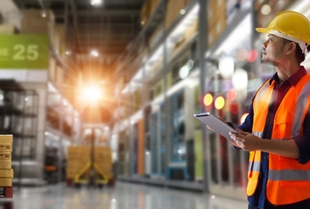 trader worker in orange vest and hardhat in a warehouse