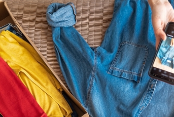 Person takes photo of button-up shirt with more clothes next to them