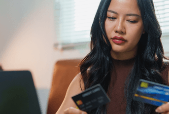 Woman looking at two credit cards