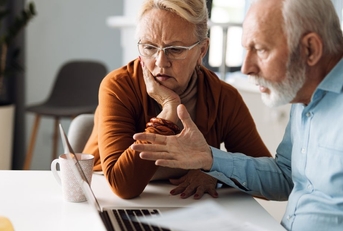 frustrated senior couple on laptop