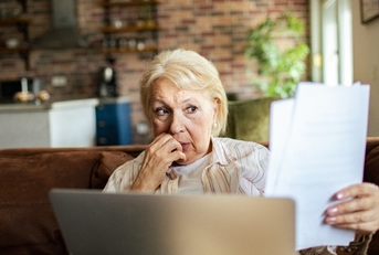 Older woman looking at papers worried face