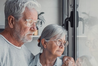 Pensive senior couple looking out window