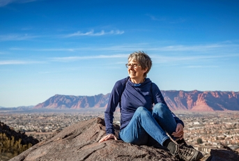 Older woman sitting on a rock during hike in mountain desert