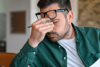 person rubbing eyes at desk