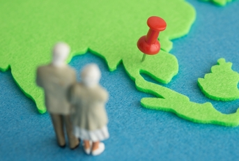 Old couple figurine looking at map with red pin 