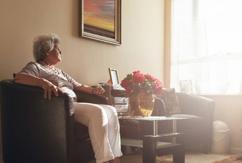 Senior woman sitting alone on a chair at home