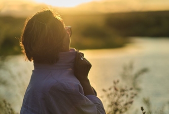 Retiree woman overlooking a river at sunset