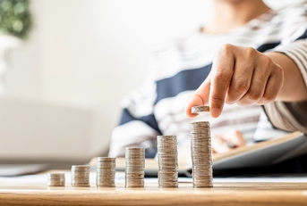 Woman adding coins to the last pile as it slowly shows growth of wealth