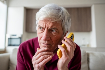 Older man on the phone looking suspicious